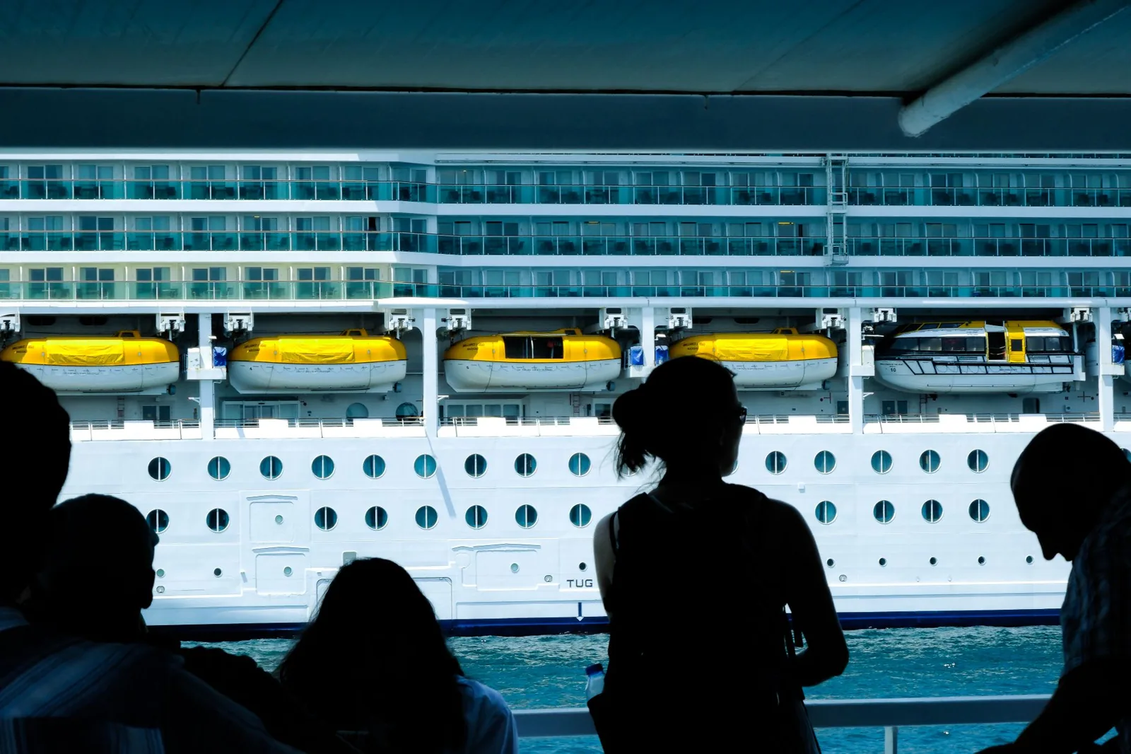 Traveler looking at a cruise ship from a deck with luggage nearby